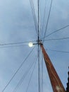 A street lamp on an electric pole with lots of wires is seen from below against a sky background. Royalty Free Stock Photo