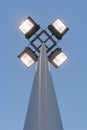 Street lamp with four floodlights shines with yellow light in the evening against a blue dark sky, perspective view from the botto Royalty Free Stock Photo