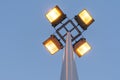 Street lamp with four floodlights shines with yellow light in the evening against a blue dark sky, perspective view from the botto Royalty Free Stock Photo