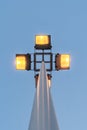 Street lamp with four floodlights shines with yellow light in the evening against a blue dark sky, perspective view from the botto Royalty Free Stock Photo