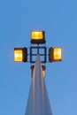 Street lamp with four floodlights shines with yellow light in the evening against a blue dark sky, perspective view from the botto Royalty Free Stock Photo