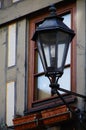 Street lamp in retro style on a house wall in front of a window with flower pots Royalty Free Stock Photo