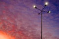 A street lamp shines against a colorful sunset sky with cirrus clouds of red color, illuminated by the setting sun Royalty Free Stock Photo