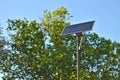 street lamp with a solar battery against a blue sky and trees Royalty Free Stock Photo