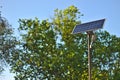 street lamp with a solar battery against a blue sky and trees Royalty Free Stock Photo