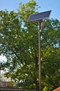 street lamp with a solar battery against a blue sky and trees Royalty Free Stock Photo