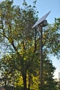 street lamp with a solar battery against a blue sky and trees Royalty Free Stock Photo