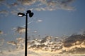 Street lamp under a blue cloudy sky during a beautiful sunset with a plane flying through it Royalty Free Stock Photo