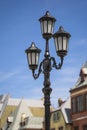 Street lamppost against the old buildings background. Classic victorian street lamps on an old fashioned iron lamp post set Royalty Free Stock Photo