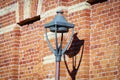 Street lantern street limp in bright sunlight with dark shadow on red brick wall Royalty Free Stock Photo