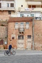 Street life in summer in Chania, Crete, Greece. Man driving on a bicycle in front of an old building