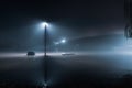 A street light standing in flood water with a bridge behind on a spooky, misty night, with a blue moody edit