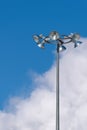 A tall lamppost with six lamps against a cloudy sky