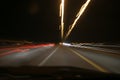 Street lights in speeding car in night time, light motion with slow speed shutter view from inside front of car. Royalty Free Stock Photo