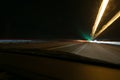 Street lights in speeding car in night time, light motion with slow speed shutter view from inside front of car.