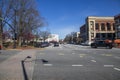 A street lined with lined with shops, restaurants, office buildings and bars with parked cars with a gorgeous blue sky