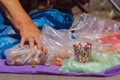 Street mart on asphalt. Old woman holds packet with potato.