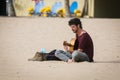 Street musician with a guitar sitting at sandy beach of Tenerife island, Spain