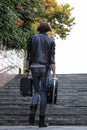 Street musician holding a case with a guitar and amplifier. It rises up the stairs of the underpass. Vagrant lifestyle. Playing to