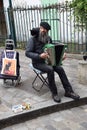 Street musician playing an accordian with a black cat on his shoulder. Paris, France. March 31, 2023. Royalty Free Stock Photo