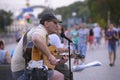 Street musician playing the guitar and singing into the microphone, blurred people on a background Royalty Free Stock Photo