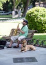 A street musician playing the saxophone in the park. A busker with his cute dog. Royalty Free Stock Photo