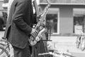 Street musician`s hands playing saxophone and double-bass in an urban environment. Black and white picture