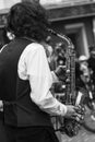 Street musician`s hands playing saxophone in an urban environment. Black and white picture