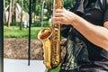 Street musician saxophonist plays jazz music in park in sunny day Royalty Free Stock Photo