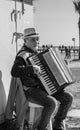 A street musician wearing a hut plays the accordeon seated at the Finikoudes Beach in Larnaca