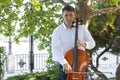 Street musician, young man playing cello in the street of big city, close up Royalty Free Stock Photo