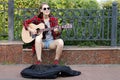 Street musician young woman playing acoustic guitar and singing in a city park