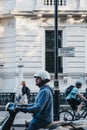 Street name sign for Buckingham Gate, London, cyclist and biker in front, woman walking on the background