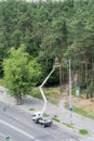 On the street near the forest, an electrician in a crane bucket is repairing a street lamp. Working repair of a street lamp at a Royalty Free Stock Photo