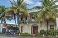 Street with an old building, green palms and a ricksha on the road