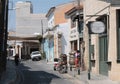 Street of the old city of Larnaca. Two bars on the left side of the photo. On the street, a man and a woman, a motorcycle and a