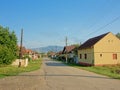 Street in the old Romanian village Aurel Vlaicu with transylvanian mountains in the background