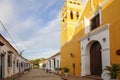 Typical street with one story buildings in sun and shadow and yellow church, Santa Cruz de Mompox, Colombia, World Heritage Royalty Free Stock Photo