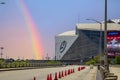 A street with orange cones and cars driving surrounded by Mercedes-Benz Stadium, lush green trees with a gorgeous clear blue sky