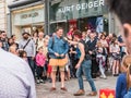 Street performer jokes with male onlooker wearing ballet tutu