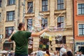 Street performer makes big bubbles on city street to entertain children and tourists. Royalty Free Stock Photo