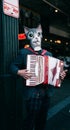 Street performer playing accordion masked as a cat next to towing sign on Seattle