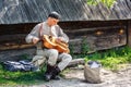 Street performer in ukrainian national costume plays hand barrel organ (hurdy-gurdy, wheel fiddle).