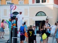 Street performer in white suit and fabulous hat makes inflatable toys out of long latex rubber balloons. Performance for children