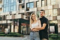 Street photo beautiful stylish young couple hugging against the backdrop of a modern building, looking in camera and smiling. Royalty Free Stock Photo