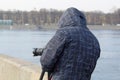 Street photographer in the process of shooting city landscapes. A camera on a tripod. A photographer in a jacket with a hood. Royalty Free Stock Photo