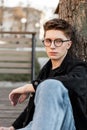 Street portrait american young hipster man with stylish glasses in fashionable denim wear in city. Handsome modern guy in trendy Royalty Free Stock Photo