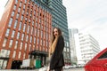 Street portrait of an attractive girl with long hair, wearing a black jacket, looking in camera and smiling. Happy beautiful woman Royalty Free Stock Photo