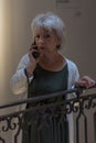 Street portrait of an elderly happy woman 65-70 years old on a blurred urban background of a European street.