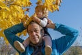 Street portrait of an elderly man holding a little girl on his shoulders. Concept: children and parents, paternal care of the daug